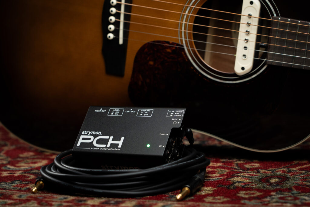 Strymon PCH sitting in front of an acoustic guitar with a pickup.